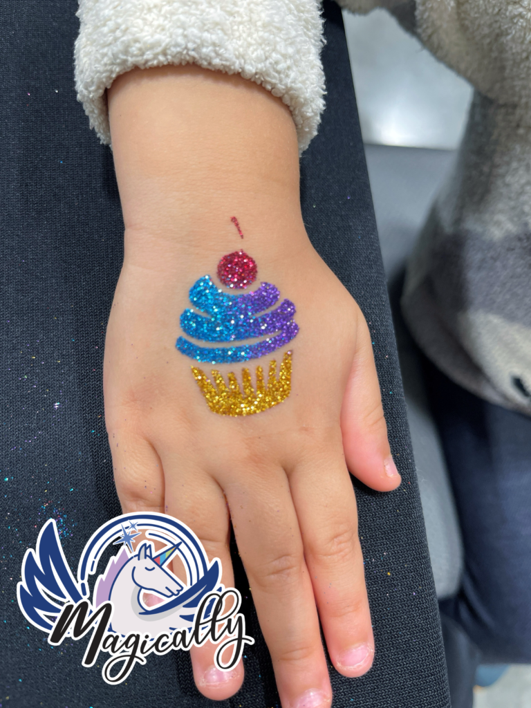 Glitter tattoo of a colorful cupcake design, featuring sparkling details and a fun, festive look!