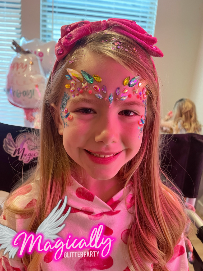 Sweet girl with sparkling gems on her face, showcasing a fun and colorful design from the glitter bar.